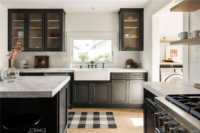 3702 Seneca Ave, Los Angeles, CA 90039 - kitchen with washer / dryer, backsplash, light wood finished floors, light stone countertops, and glass insert cabinets