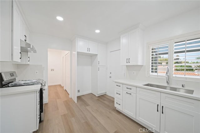 3704 Lorado Way, View Park, CA 90043 - kitchen with stainless steel stove, under cabinet range hood, light wood finished floors, white cabinets, and light countertops
