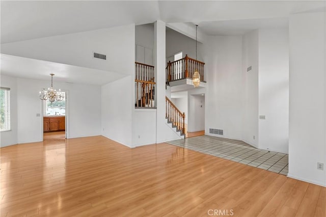 44051 Sheldon Ct, Temecula, CA 92592 - unfurnished living room with a chandelier, wood finished floors, high vaulted ceiling, and stairs