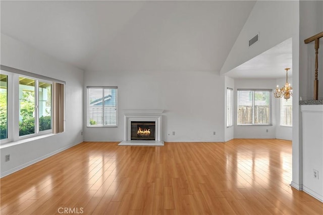 44051 Sheldon Ct, Temecula, CA 92592 - unfurnished living room featuring healthy amount of natural light, a chandelier, a glass covered fireplace, light wood finished floors, and vaulted ceiling