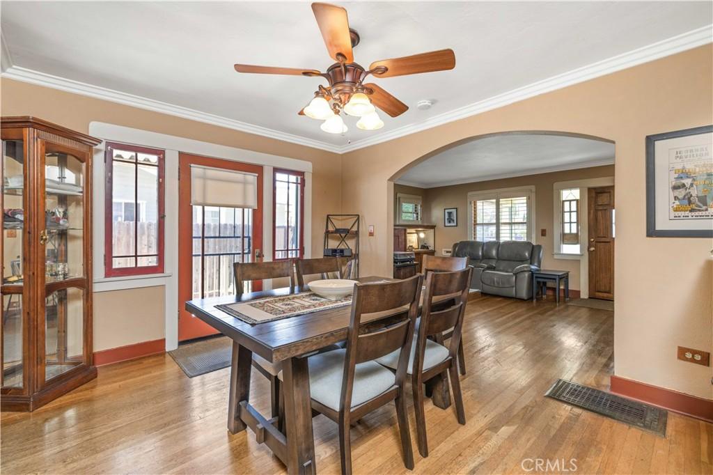 573 E Alvarado St, Pomona, CA 91767 - dining area featuring arched walkways, light wood-style floors, crown molding, and ceiling fan