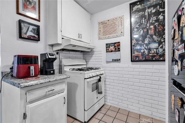 2660 Newell St, County Los Angeles, CA 90039 - kitchen featuring white gas range oven, under cabinet range hood, light tile patterned floors, white cabinetry, and light countertops