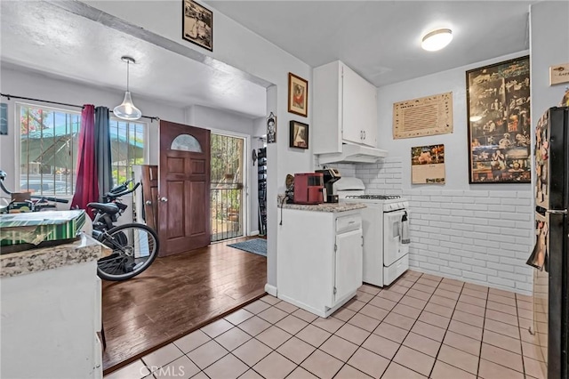 2660 Newell St, County Los Angeles, CA 90039 - kitchen with white gas range oven, light countertops, white cabinets, under cabinet range hood, and freestanding refrigerator
