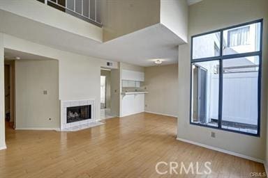 16857 San Fernando Mission Blvd Unit 7, Granada Hills, CA 91344 - unfurnished living room with a fireplace with flush hearth, wood finished floors, and a towering ceiling