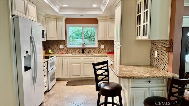 3001 Via Buena Vis Unit C, Laguna Woods, CA 92637 - kitchen featuring white appliances, a kitchen bar, light stone countertops, decorative backsplash, and ornamental molding