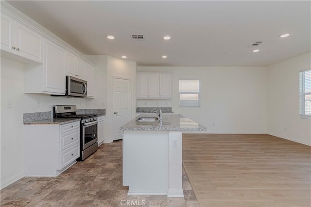24679 Acadia Dr, Corona, CA 92883 - kitchen with appliances with stainless steel finishes, white cabinets, recessed lighting, a center island with sink, and light stone counters