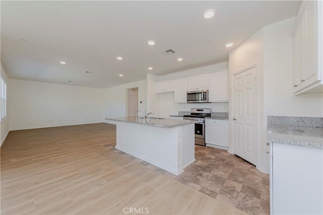 24679 Acadia Dr, Corona, CA 92883 - kitchen featuring appliances with stainless steel finishes, white cabinets, recessed lighting, open floor plan, and light stone counters