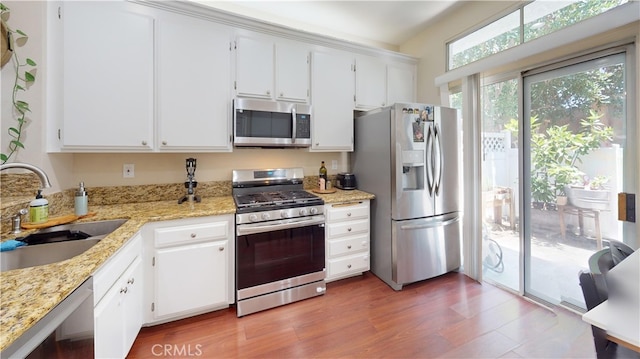28305 Paseo El Siena Unit 10, Laguna Niguel, CA 92677 - kitchen featuring stainless steel appliances, white cabinets, light stone countertops, and wood finished floors