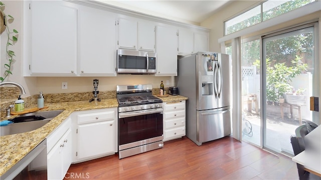 28305 Paseo El Siena Unit 10, Laguna Niguel, CA 92677 - kitchen featuring stainless steel appliances, white cabinets, light stone counters, and wood finished floors