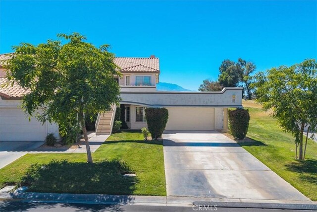 191 Desert Falls Cir, Palm Desert, CA 92211 - view of front of house with a front lawn, concrete driveway, an attached garage, and a tiled roof