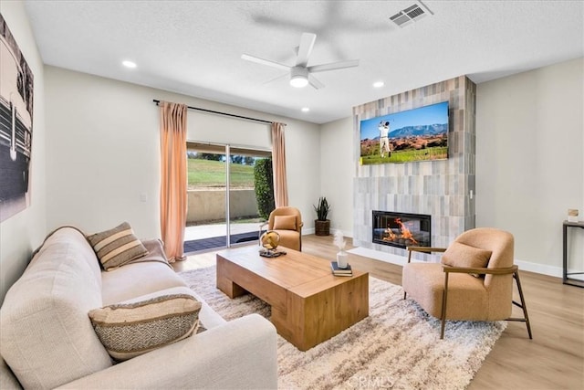 191 Desert Falls Cir, Palm Desert, CA 92211 - living room featuring a tile fireplace, a textured ceiling, light wood-style floors, a ceiling fan, and recessed lighting