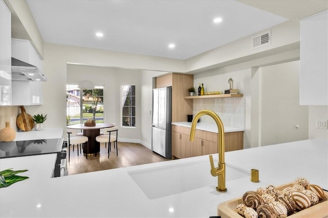 191 Desert Falls Cir, Palm Desert, CA 92211 - kitchen with appliances with stainless steel finishes, ventilation hood, light countertops, wood finished floors, and recessed lighting