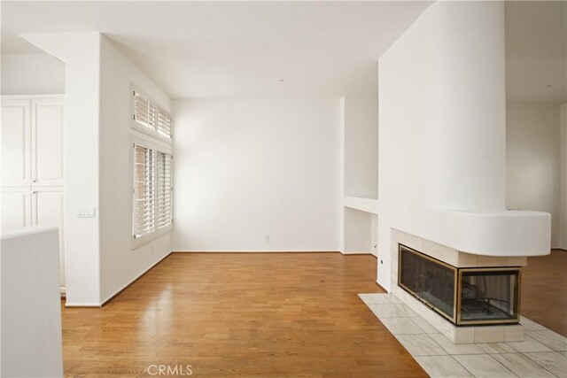 6 Garzoni Aisle, Irvine, CA 92606 - unfurnished living room featuring light wood-style flooring and a tile fireplace