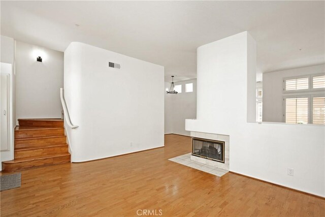 6 Garzoni Aisle, Irvine, CA 92606 - unfurnished living room featuring wood finished floors, a fireplace, stairs, and a chandelier