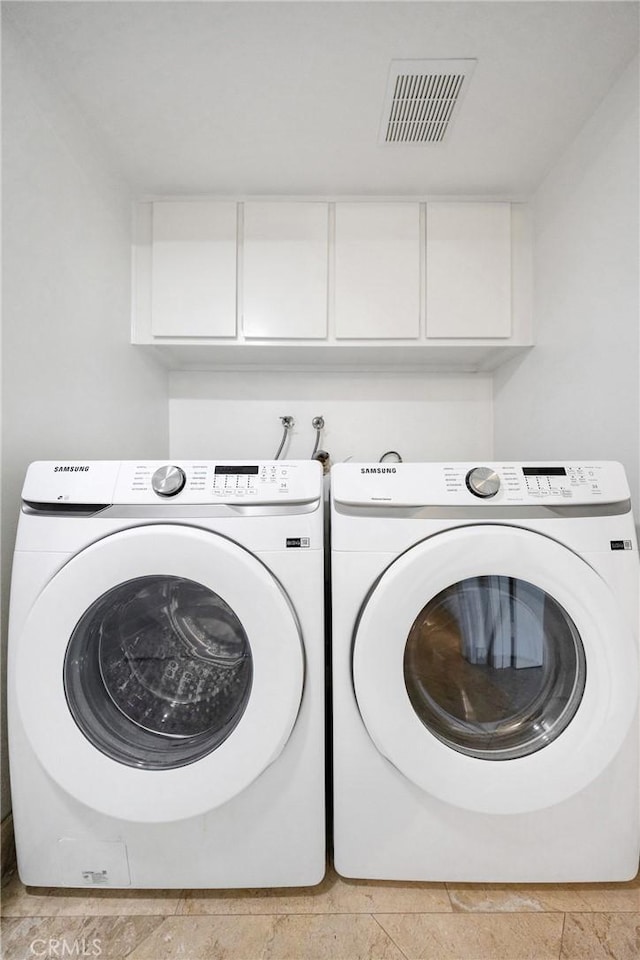 20 Nuevo Unit 10, Irvine, CA 92612 - laundry area featuring cabinet space, washing machine and dryer, and stone tile floors