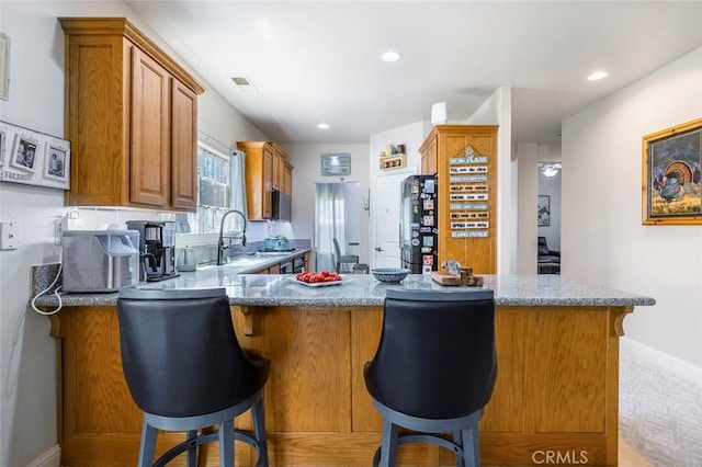 6 N Post Ave, Sanger, CA 93657 - kitchen featuring brown cabinets, black fridge, light stone countertops, a breakfast bar area, and recessed lighting