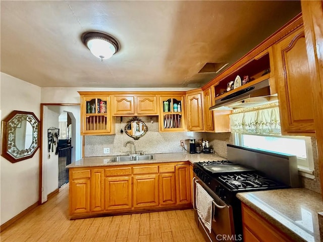 1246 W Mill St, San Bernardino, CA 92410 - kitchen featuring stainless steel range with gas cooktop, under cabinet range hood, light wood finished floors, arched walkways, and light countertops