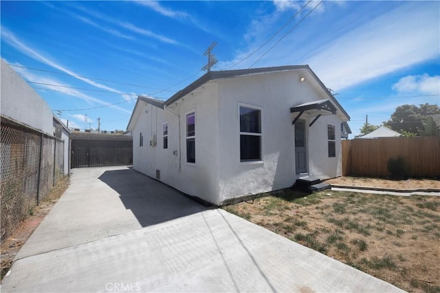 147114711/2 E 41st Pl, Los Angeles, CA 90011 - view of side of home featuring stucco siding, a fenced backyard, and driveway
