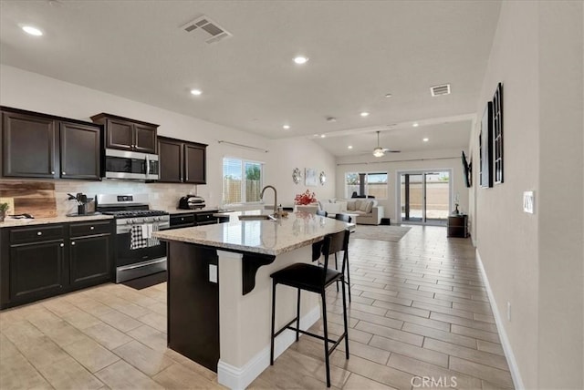 2454 W Mallard Ln, Hanford, CA 93230 - kitchen with stainless steel appliances, backsplash, open floor plan, a kitchen breakfast bar, and an island with sink