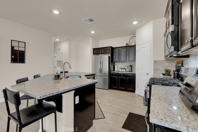 2454 W Mallard Ln, Hanford, CA 93230 - kitchen featuring appliances with stainless steel finishes, backsplash, a center island with sink, a kitchen breakfast bar, and recessed lighting
