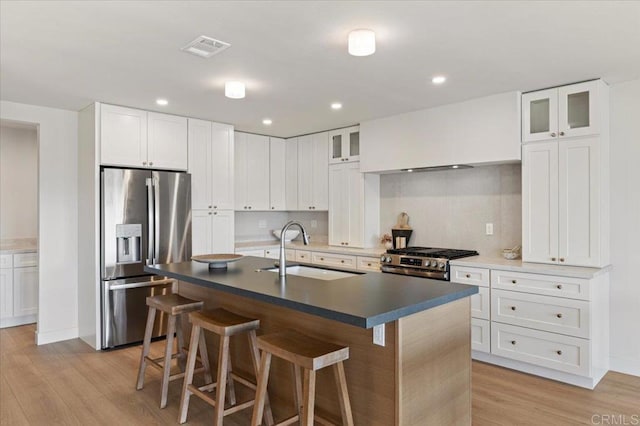 1515 San Pablo Dr, San Marcos, CA 92078 - kitchen featuring stainless steel appliances, a kitchen bar, light wood finished floors, glass insert cabinets, and a center island with sink