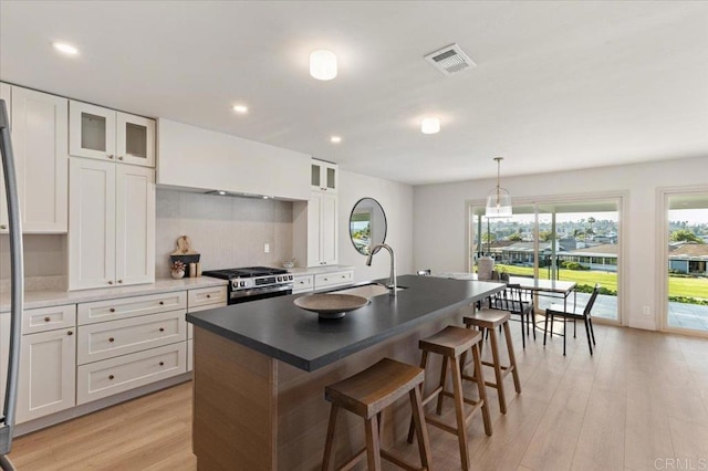 1515 San Pablo Dr, San Marcos, CA 92078 - kitchen with stainless steel range with gas cooktop, light wood-style floors, a breakfast bar, a kitchen island with sink, and white cabinets
