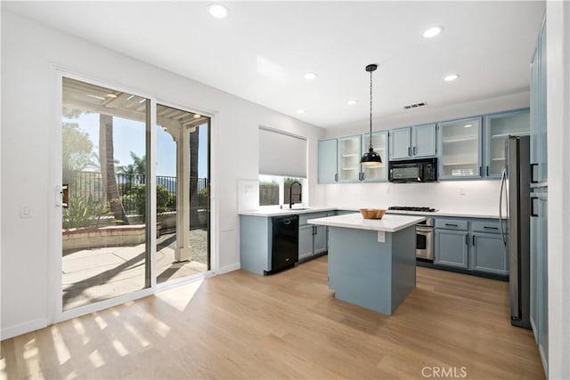 33307 Decada St, Temecula, CA 92592 - kitchen with black appliances, light wood-style flooring, a kitchen island, light countertops, and glass insert cabinets