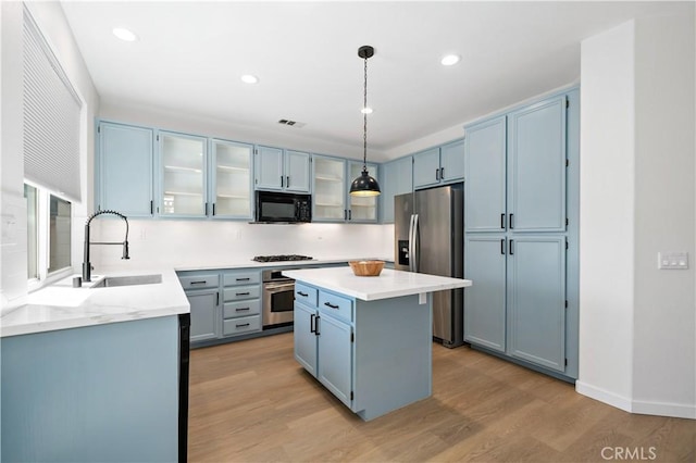33307 Decada St, Temecula, CA 92592 - kitchen with appliances with stainless steel finishes, light wood finished floors, blue cabinets, a kitchen island, and recessed lighting