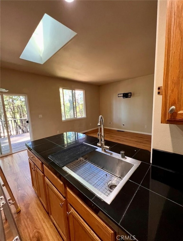 1290 Tuck Rd, Willits, CA 95490 - kitchen featuring light wood-type flooring, brown cabinetry, plenty of natural light, and a skylight