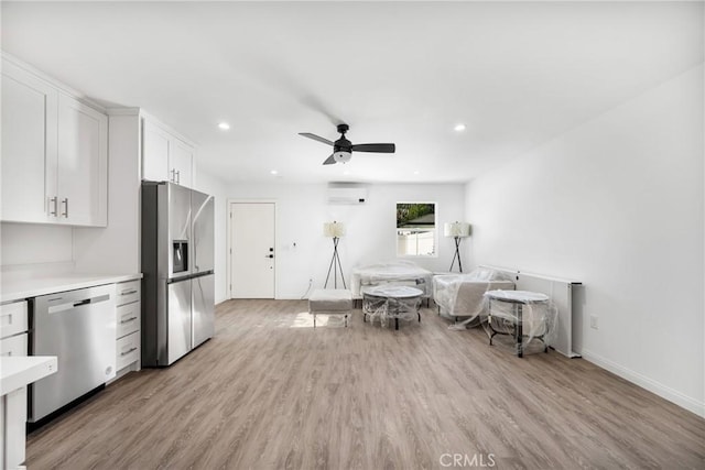 4851 Faculty Ave, Long Beach, CA 90808 - kitchen featuring stainless steel appliances, a wall mounted AC, light countertops, white cabinets, and light wood-style floors