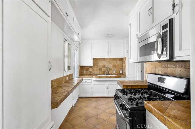 4851 Faculty Ave, Long Beach, CA 90808 - kitchen with gas range oven, stainless steel microwave, tasteful backsplash, white cabinets, and tile countertops