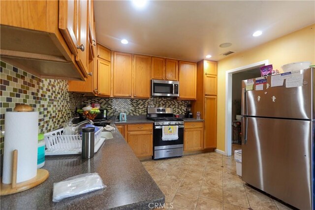 4981 Tulsa Ave, Riverside, CA 92505 - kitchen featuring appliances with stainless steel finishes, dark countertops, tasteful backsplash, recessed lighting, and light tile patterned flooring