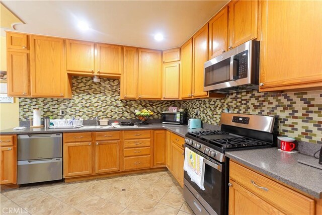 4981 Tulsa Ave, Riverside, CA 92505 - kitchen featuring stainless steel appliances, backsplash, dark countertops, and light tile patterned floors