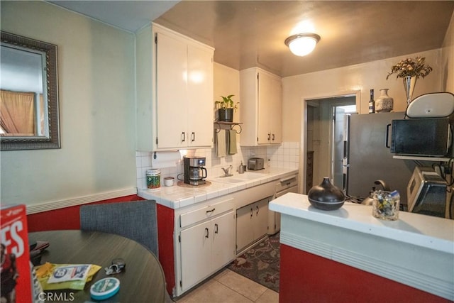 290 W 19th St, Long Beach, CA 90806 - kitchen featuring white cabinetry, tasteful backsplash, tile counters, light tile patterned floors, and freestanding refrigerator