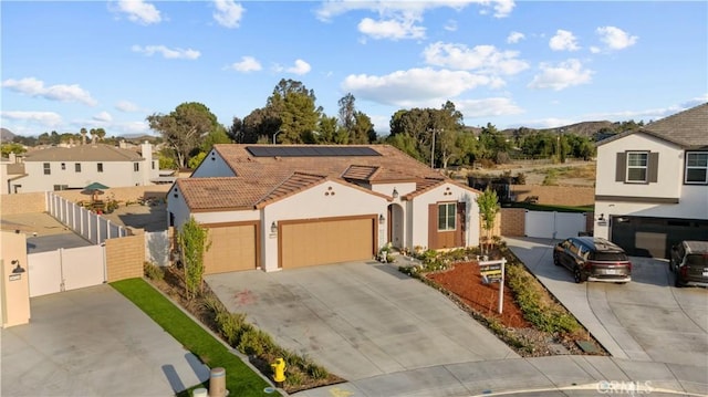 26719 Evergreen, Menifee, CA 92584 - view of front facade with driveway, stucco siding, roof mounted solar panels, a gate, and a tile roof