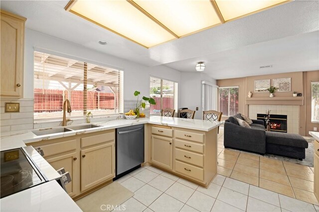 37826 Sweetbrush St, Palmdale, CA 93552 - kitchen with stainless steel dishwasher, a peninsula, range with electric stovetop, light countertops, and a tile fireplace