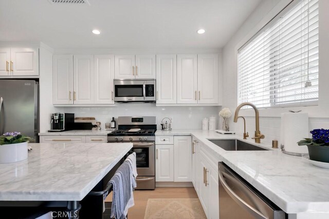 23451 Friar St, Woodland Hills, CA 91367 - kitchen with appliances with stainless steel finishes, white cabinets, light stone counters, recessed lighting, and light wood-type flooring