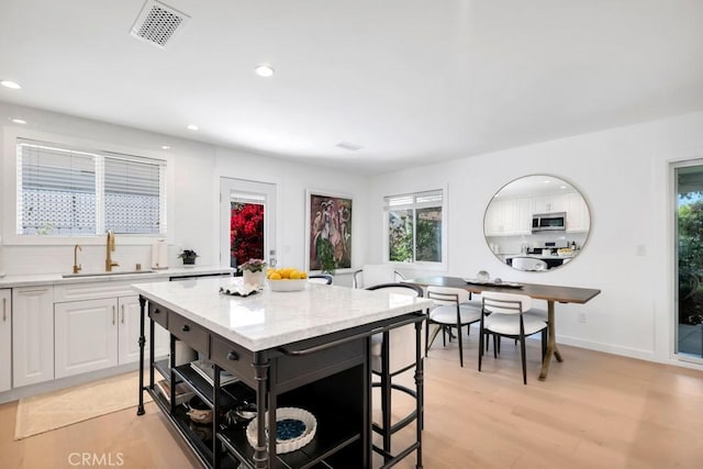 23451 Friar St, Woodland Hills, CA 91367 - kitchen featuring stainless steel microwave, white cabinets, recessed lighting, light stone countertops, and a kitchen bar