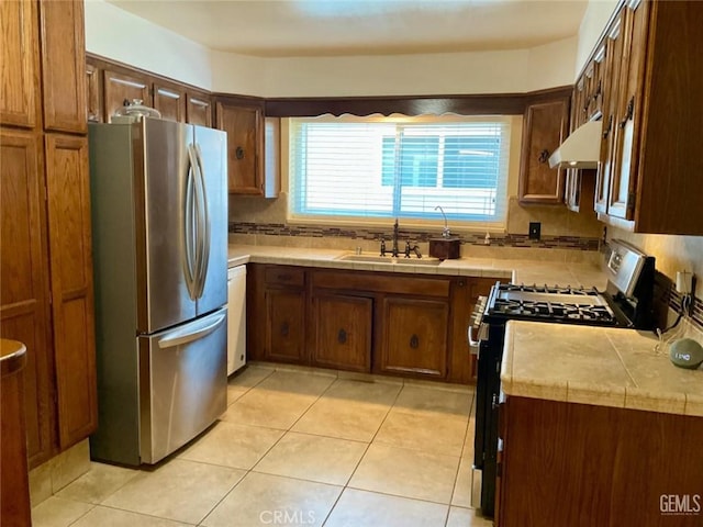2720 Baylor St, Bakersfield, CA 93305 - kitchen with freestanding refrigerator, black range with gas stovetop, under cabinet range hood, and light tile patterned floors