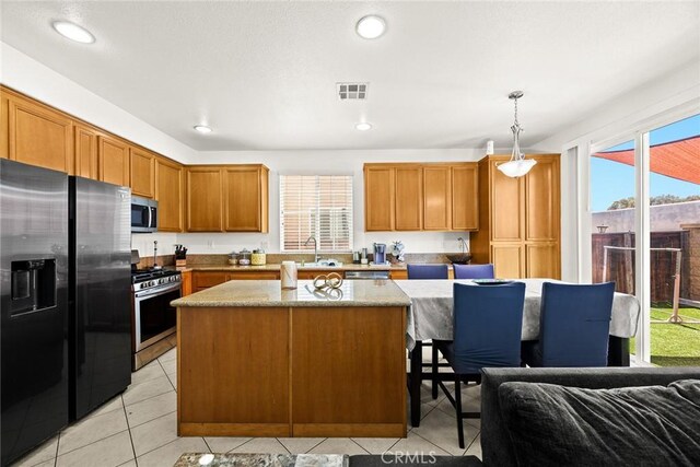 1711 Lordsburg Ct, La Verne, CA 91750 - kitchen with stainless steel appliances, a center island, light tile patterned floors, brown cabinetry, and hanging light fixtures