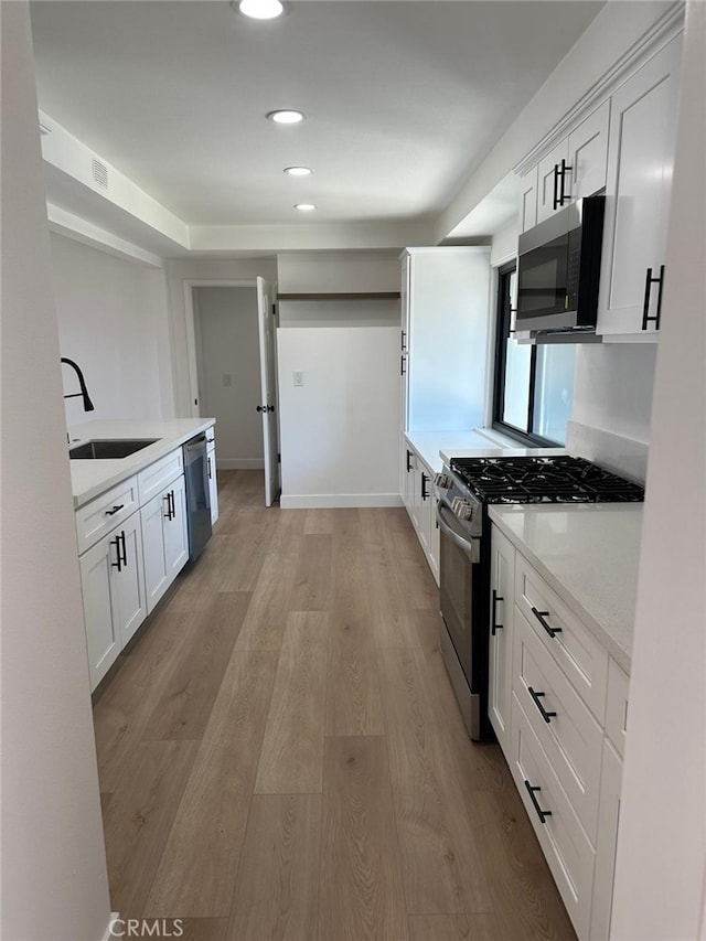 259 Freda Ave, Pomona, CA 91767 - kitchen featuring appliances with stainless steel finishes, light wood-style flooring, light countertops, white cabinetry, and recessed lighting