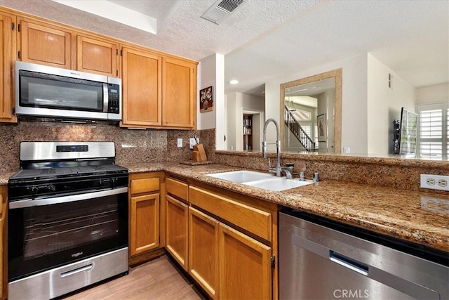 1413 Daisy St, Upland, CA 91784 - kitchen featuring stainless steel appliances, decorative backsplash, light wood-style flooring, light stone countertops, and a textured ceiling