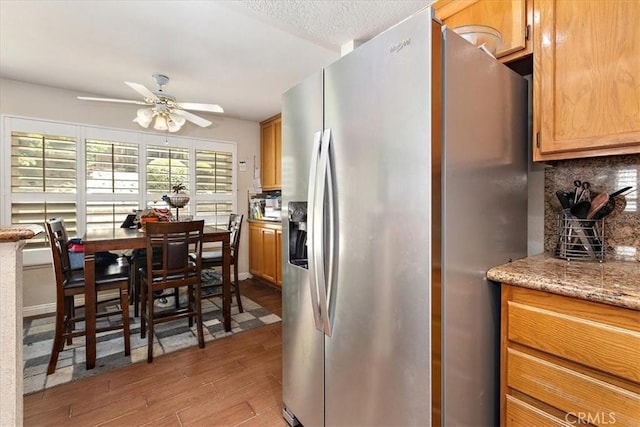 1413 Daisy St, Upland, CA 91784 - kitchen with stainless steel refrigerator with ice dispenser, light wood-style flooring, ceiling fan, light stone counters, and decorative backsplash