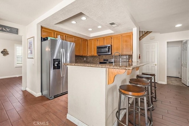 1413 Daisy St, Upland, CA 91784 - kitchen featuring appliances with stainless steel finishes, tasteful backsplash, recessed lighting, a peninsula, and light stone counters
