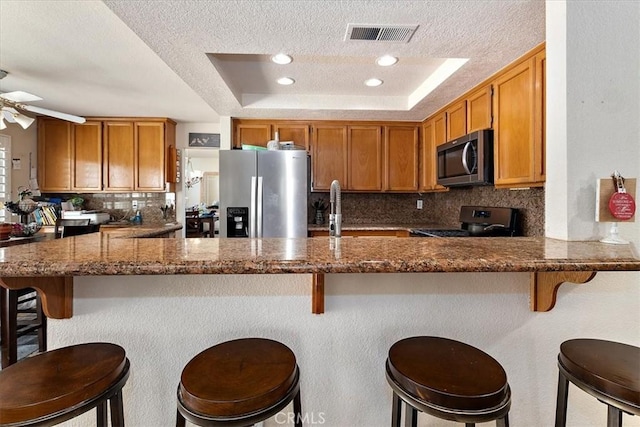 1413 Daisy St, Upland, CA 91784 - kitchen featuring stainless steel appliances, a textured ceiling, backsplash, dark stone counters, and brown cabinetry