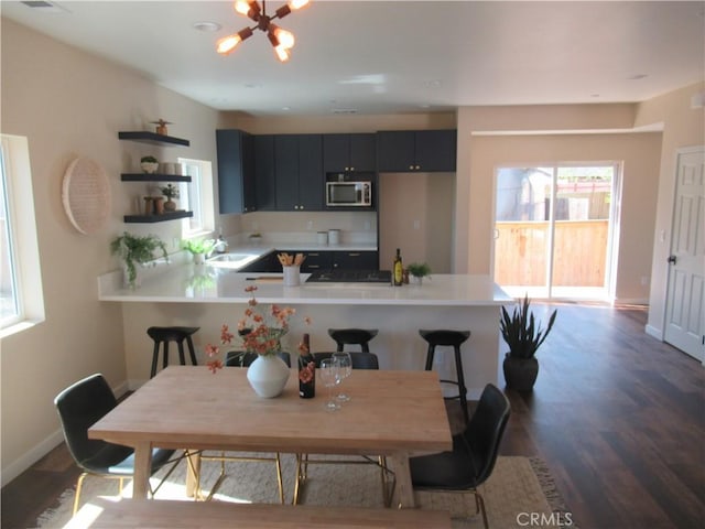7906 Curbaril Ave, Atascadero, CA 93422 - kitchen with stainless steel microwave, open shelves, a peninsula, light countertops, and dark wood-style floors