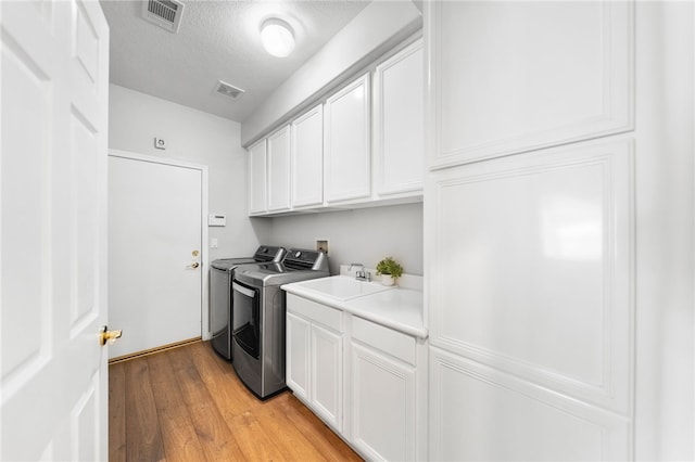 12554 Tejas Ct, Rancho Cucamonga, CA 91739 - laundry area with washing machine and dryer, cabinet space, light wood-style flooring, and a textured ceiling