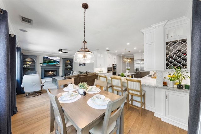 12554 Tejas Ct, Rancho Cucamonga, CA 91739 - dining space with a lit fireplace, light wood-style floors, ceiling fan, recessed lighting, and crown molding