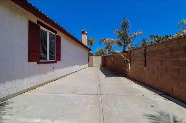 26946 Shelter Cove Ct, Menifee, CA 92585 - view of side of home featuring stucco siding, a patio area, and a chimney