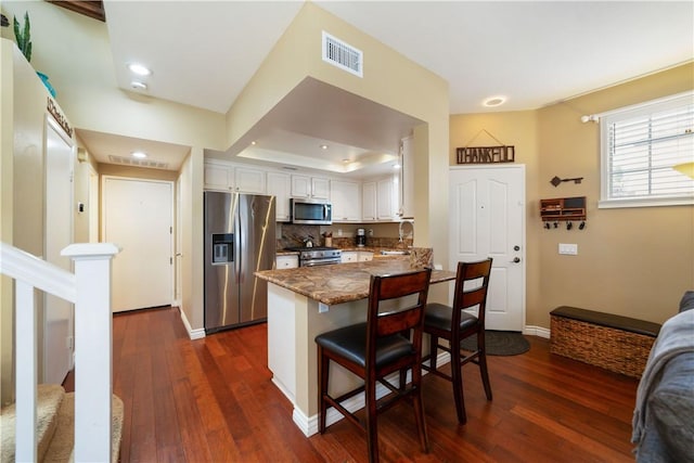 51 Rue Monet, Lake Forest, CA 92610 - kitchen with stainless steel appliances, a peninsula, white cabinetry, dark wood-style floors, and recessed lighting